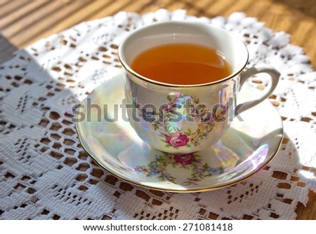 china painted cup of tea with pattern of flowers lying on the white tablecloth