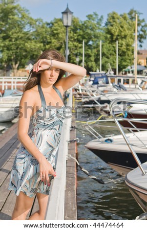 A beautiful fashion woman staying near boats, on marina