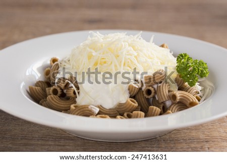 whole wheat pasta with cheese and sour cream of a palm on the table.