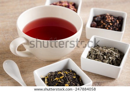 a cup of tea, four different kind tea, in white dish on the table