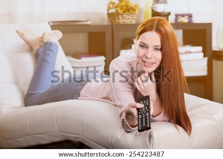 Woman watching television and switch with the remote control in the room.