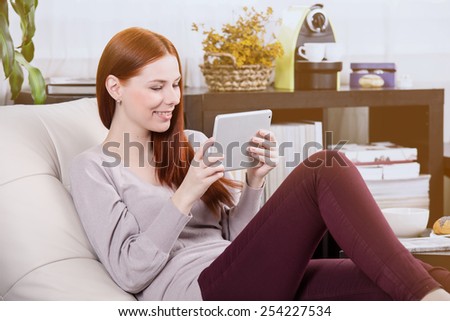 Thin girl read the tablet on the sofa in the room.
