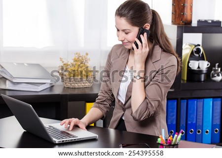Elegant business woman talking on land line telephone and work on the notebook in the office.