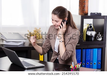Elegant business woman talking on telephone and work on the notebook in the office.