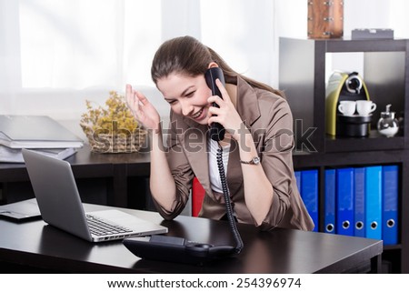 Elegant business woman talking on land line telephone and work on the notebook in the office.