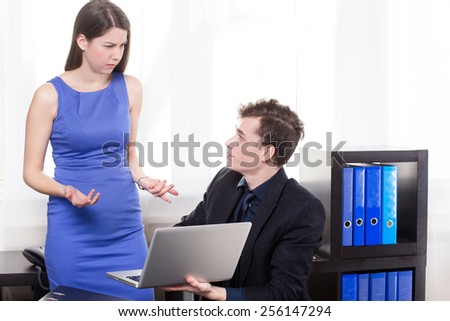 a business man shows the laptop to his colleague in the office.
