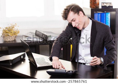 Business man call someone on the landing phone and drinking coffee in the office