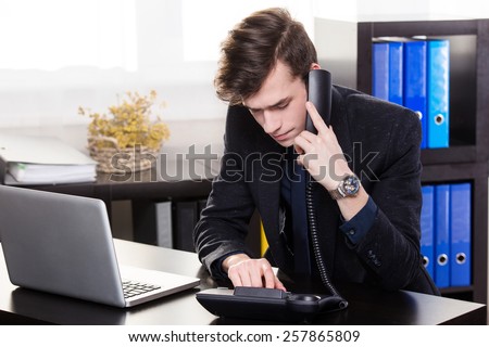 Business man call someone on the landing phone in the office