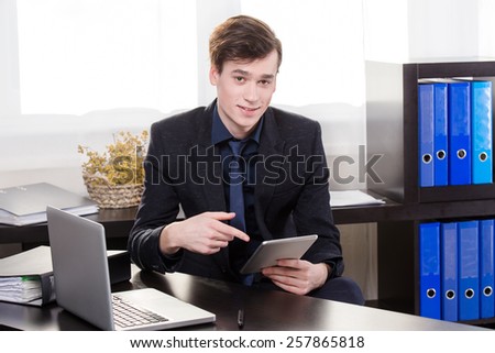 Elegant business man show the tablet in the office.