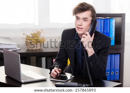 Business man call someone on the landing phone and use the tablet in the office
