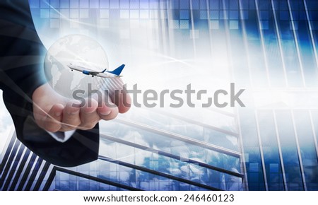 Young businessman holding airplane and digital earth, background buildings