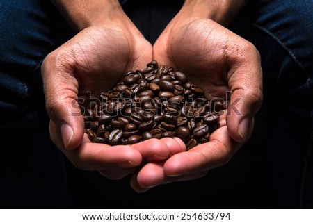 Man holding coffee beans in cupped hands, close-up
