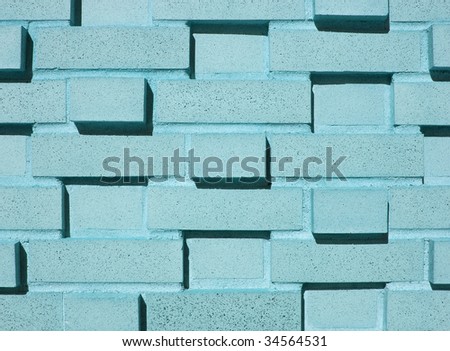 A pastel blue, teal or aqua multi-layered and multi-sized brick wall.