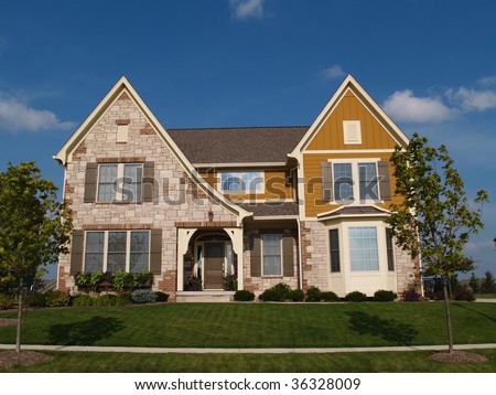 Two story stone, brick and board sided residential home with bay window.