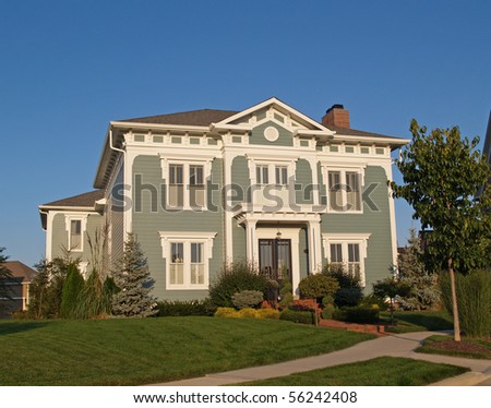 A new home constructed to look like an old two story historical home with green siding and white trim.