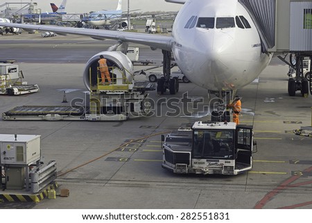 YSBRECHTUM, THE NETHERLANDS - MAY 30, 2015: Photo of two ground crew workers in orange safety clothes working on a Airbus A 310 connected with a passenger walkway.  Photo taken on April 30th 2015.