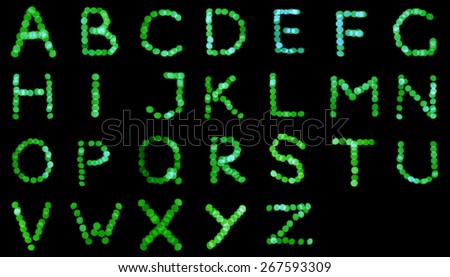 English alphabet, letters of Christmas lights, green bokeh.