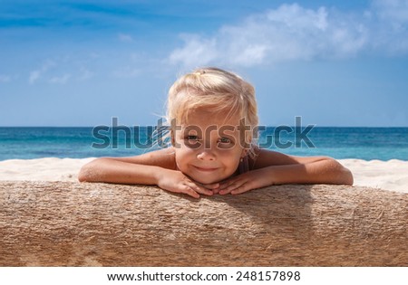 Little girl take sun bath on old coconut tree near by azure sea