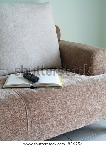 An open book with a tv remote control on a sofa couch