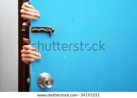Hands behind a blue door