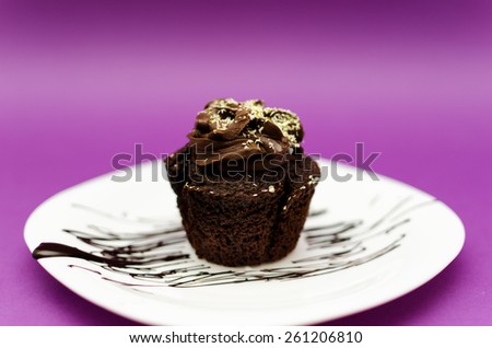 Chocolate muffin on white plate and pink background with pistachio topping