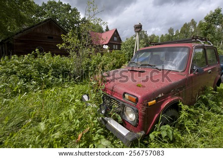 old abandoned russian red car in nettles
