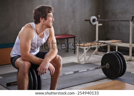 Young handsome man looking away positively in a private gym