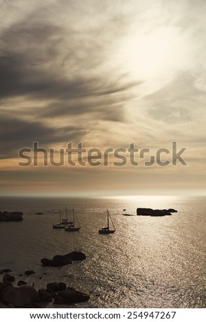 Peaceful image of boats on a calm sea with soft clouds overhead