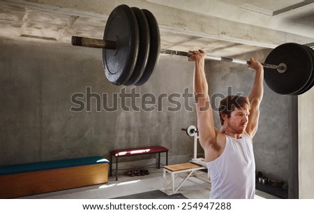 Wide angle shot of a strong man lifting very heavy training weights in a private gym