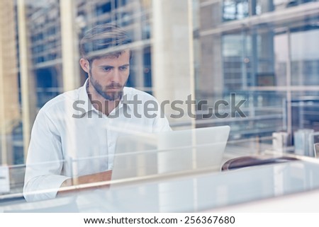 View through a window of a corporate executive working on his laptop