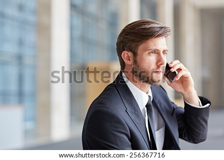 Corporate executive using his cell phone in a modern architectural setting