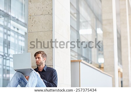 Conceptual shot of a young businessman using his laptop outside a modern building