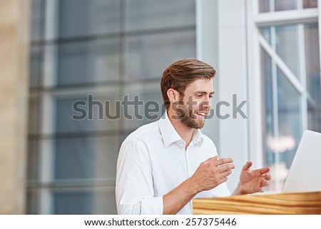 Young businessman engaged in a conversation on his laptop in a corporate setting