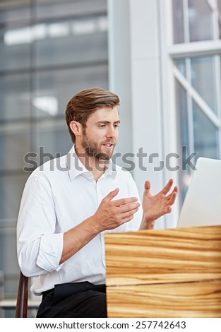 Young businessman engaged in a conversation on his laptop in a corporate setting