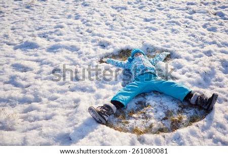 Shot of a little girl making snow angels in a snowy field