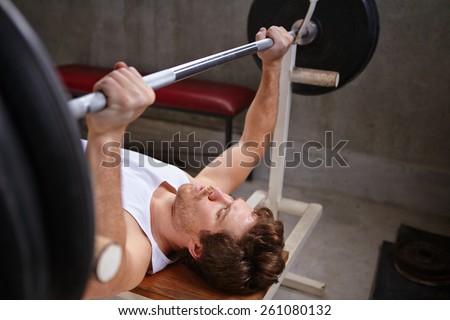 Young man lifting up weights in a private gym