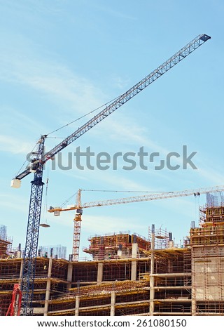 An urban building under contsruction with cranes working to move building materials on site
