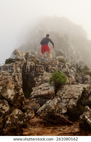 Low angle view of a young man hiking up to the top of a mountain