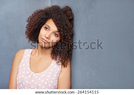 A young woman leaning against a gray wall