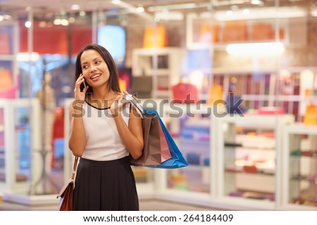 A young woman talking on the phone in a shopping mall