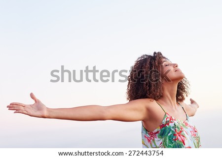 Woman outdoors with her arms outstretched and her eyes closed expressing serene freedom