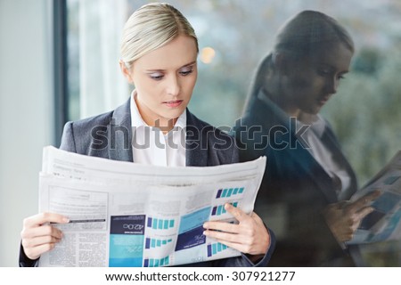 A young businesswoman reading the newpaper outside her office