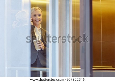 A young businesswoman talking on the phone in elevator