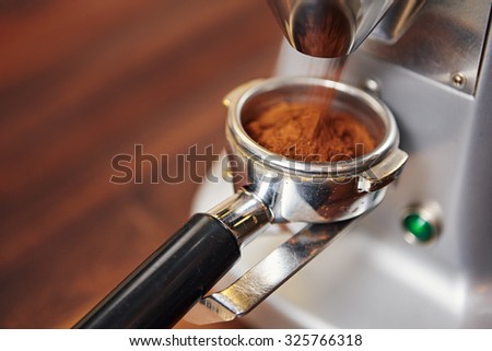 High angle view of fresh coffee pouring out of a coffee grinder into a portafilter for a professional espresso machine