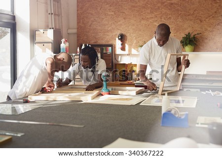 Carpenters framing pictures in their workshop