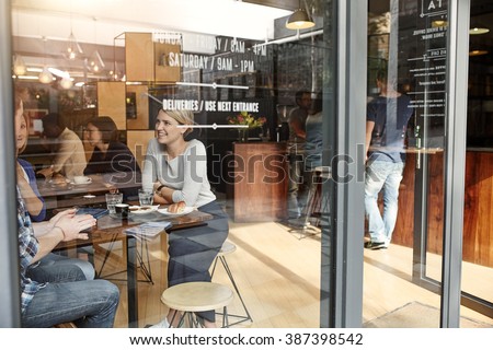 Woman with friends at a cafe seen through window