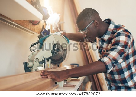 African artisan working with a chop saw in woodwork workshop