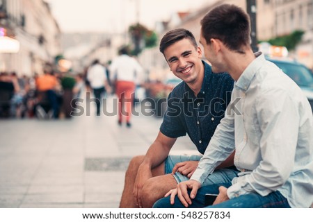 Two young friends talking together on a city street