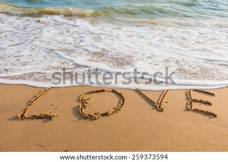 alphabet letters love handwritten in sand on beach for background