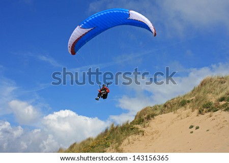 Paraglider flying over sand dunes